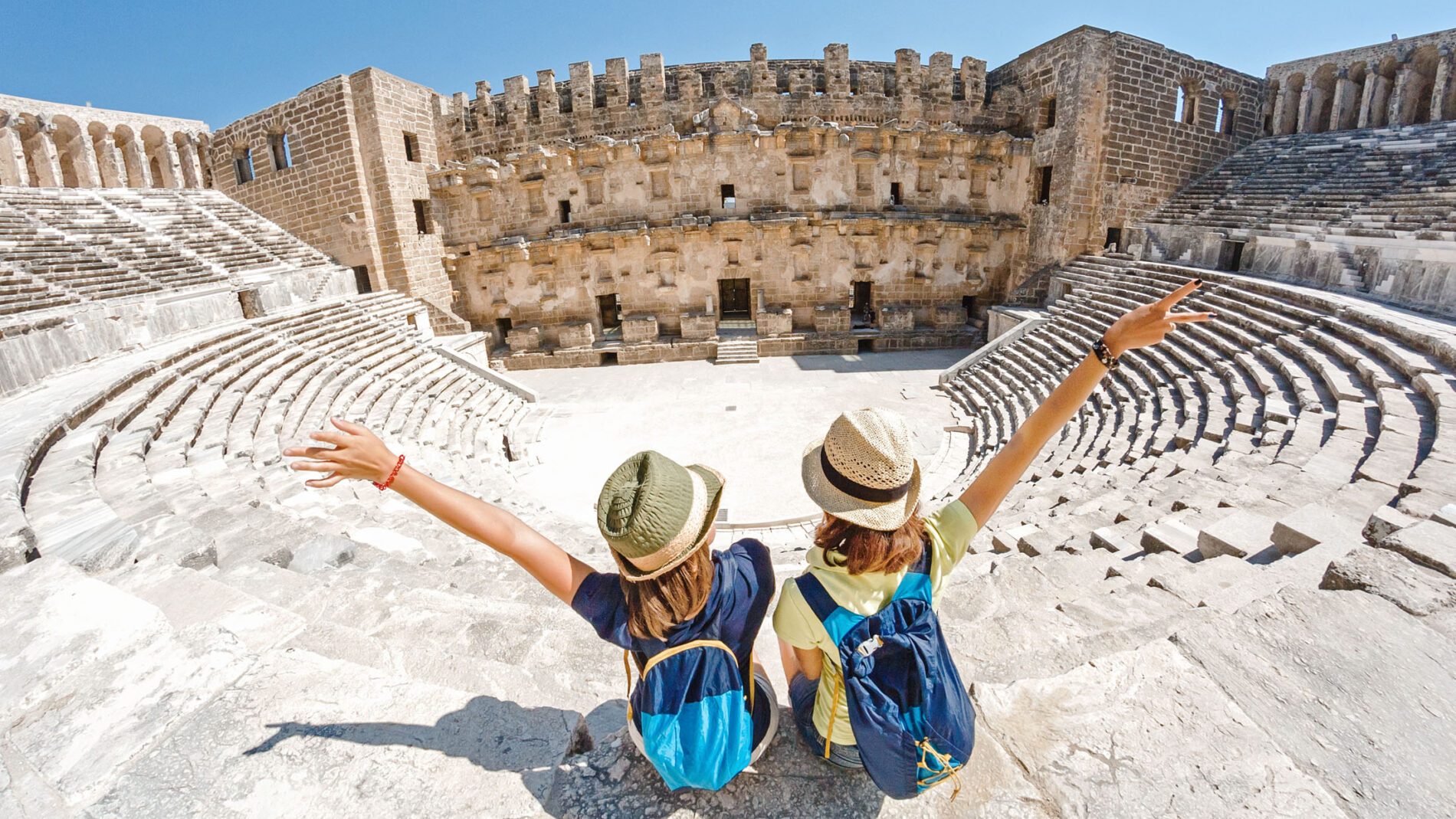 Two young girls student traveler enjoy a tour of the ancient Greek amphitheater