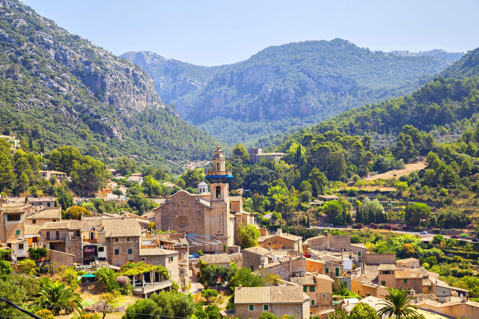 Mountain village Valldemosa in Mallorca Valldemosa Mallorca: Bergiges Dorf mit Kirchturm, umgeben von Grünland, Olivenhainen und Bergen.
